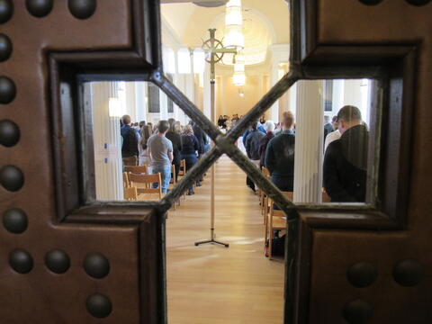 view through cross-shaped window in the door of Marquand Chapel