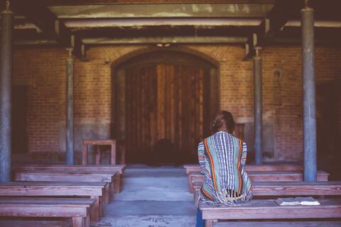 person praying alone in sanctuary