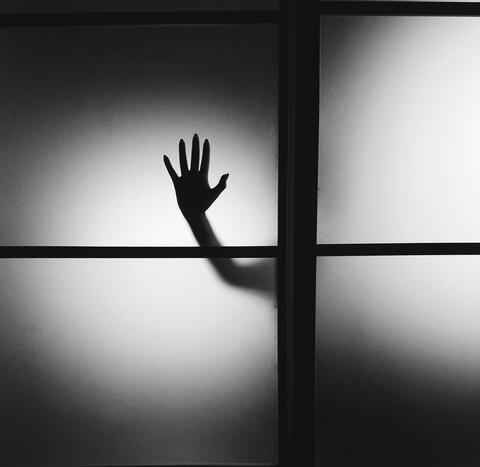 silhouette of hand on glass door