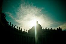 An image of the sun behind the dome in St. Peter's Square, Vatican City