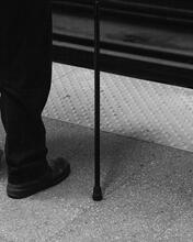 Image of a leg in black pants with a black cane beside it
