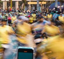cell phone held before a blurred crowd